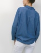 patron de couture Chemise Liseron dans une viscose bleu jean de chez Cousette porté avec un jean blanc, vue 3/4 dos main dans la poche