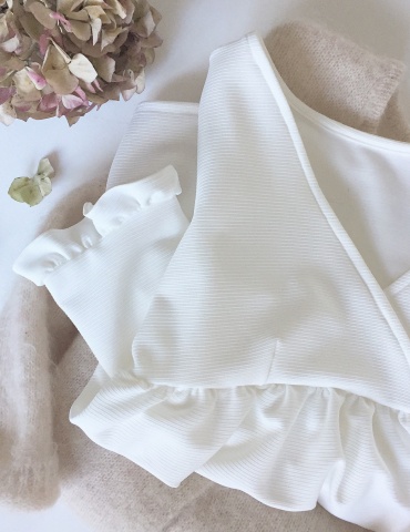 Modèle Eugenie version blouse dans un tissu blanc présenté plié sur un pull Des Petits Hauts nude