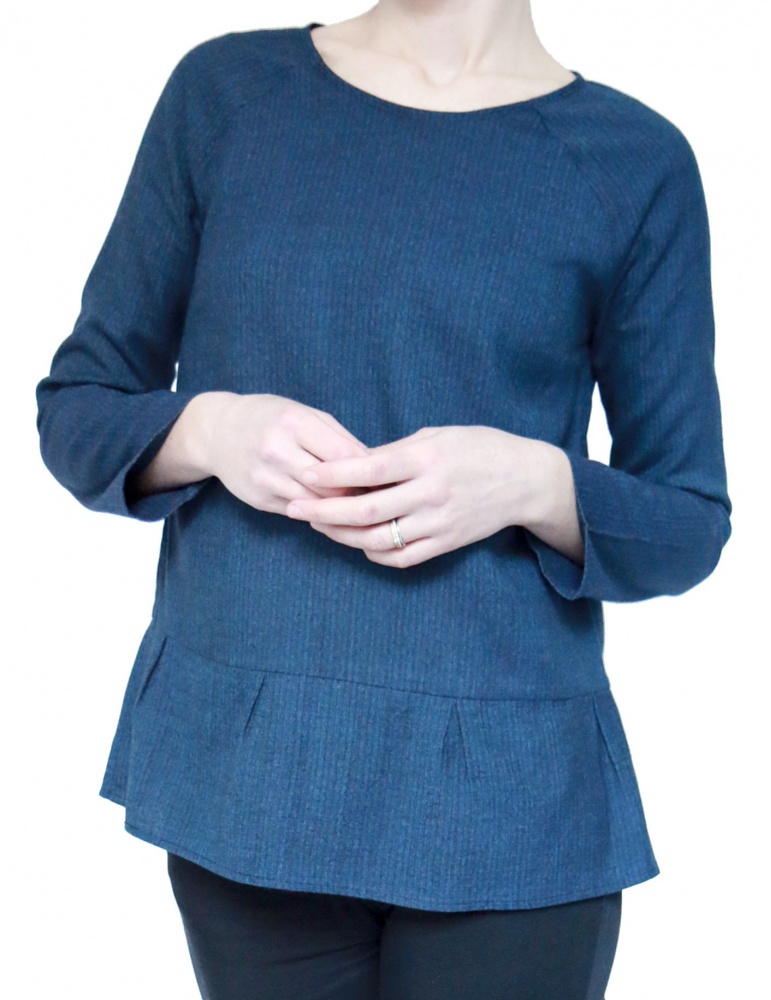 Blouse Stockholm réalisée dans un lainage fin bleu, version avec basque à plis creux au bas du top, vue de face